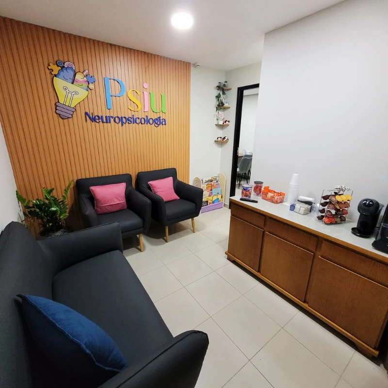 Recepção da Psiu, com a marca na parede de ripas, poltronas de espera e o cantinho do café