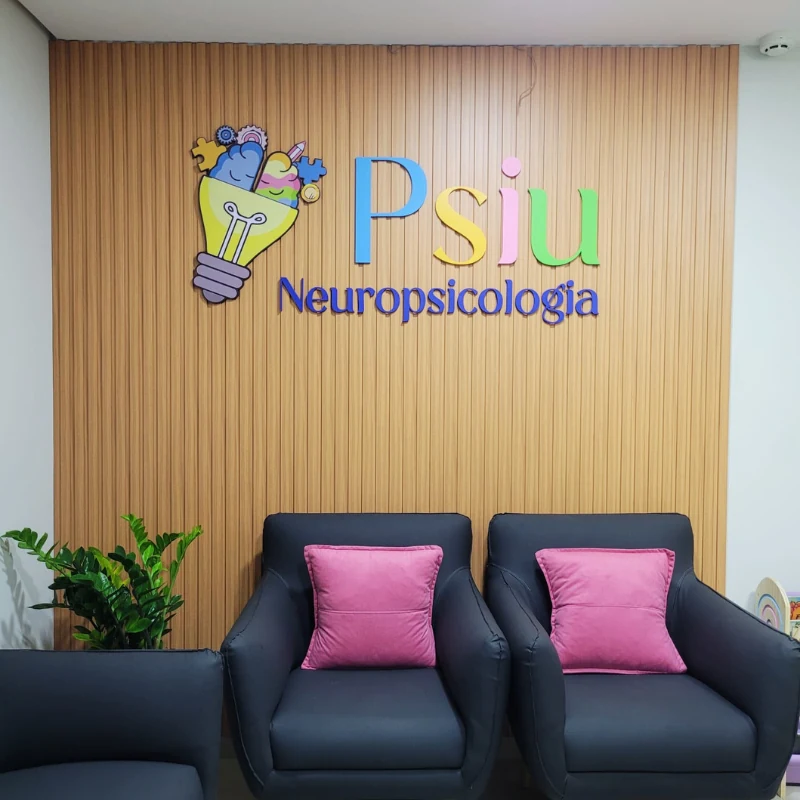 Parede da recepção com a marca Psiu e as poltronas com almofadas rosa